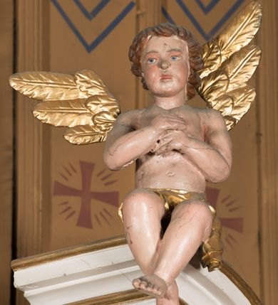 Zdjęcie nr 9: Nastawa architektoniczna, jednoosiowa, jednokondygnacyjna ze zwieńczeniem, ustawiona na dwustrefowym cokole, w górnej części z wyłamanymi pod kątem dwoma prostopadłościanami. Ołtarz drewniany, prostopadłościenny, skrzyniowy, z drewnianą mensą. Antepedium ujęte profilowaną ramą, w polu dwie, duże, płaskorzeźbione rozety na pomarańczowym tle. Nastawa ujęta parą kolumn ustawionych na tle pilastrów, dźwigających pełne belkowanie, wyłamane pod kątem na ich osi, częściowo przerwane nad polem środkowym, oraz fragmenty przerwanego półkolistego przyczółka z puttami. Pole centralne w całości wypełnione wnęką w formie stojącego prostokąta zamkniętego łukiem segmentowym nadwieszonym, ujętym profilowaną ramą, z wpisanym krucyfiksem na tle malowanych obłoków. Nad nim akantowo-wstęgowy kartusz, z napisem „OJCZE! / odpuść im / bo niewiedzą / co czynią”. Kondygnację flankują figury Matki Boskiej i św. Jana ustawione na wysuniętych krawędziach cokołu oraz uszy utworzone z suchego akantu i wstęgi. Zwieńczenie w formie zbliżonej do trapezu zamkniętego fragmentem gzymsu o kształcie łuku segmentowego z uskokiem, flankowanego spływami wolutowymi. W polu obraz Piety w formie stojącego owalu, ujęty profilowaną ramą, u góry dekorowany zwisami kwiatowymi, u dołu liśćmi. Całość zakończona figurą Anioła Stróża. Struktura polichromowana w kolorze białym; kolumny, profile i ornamentyka złocone, detal srebrzony. 