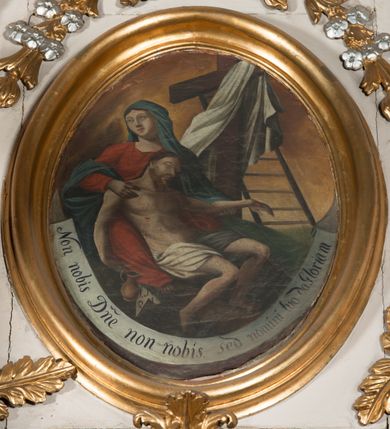 Zdjęcie nr 5: Nastawa architektoniczna, jednoosiowa, jednokondygnacyjna ze zwieńczeniem, ustawiona na dwustrefowym cokole, w górnej części z wyłamanymi pod kątem dwoma prostopadłościanami. Ołtarz drewniany, prostopadłościenny, skrzyniowy, z drewnianą mensą. Antepedium ujęte profilowaną ramą, w polu dwie, duże, płaskorzeźbione rozety na pomarańczowym tle. Nastawa ujęta parą kolumn ustawionych na tle pilastrów, dźwigających pełne belkowanie, wyłamane pod kątem na ich osi, częściowo przerwane nad polem środkowym, oraz fragmenty przerwanego półkolistego przyczółka z puttami. Pole centralne w całości wypełnione wnęką w formie stojącego prostokąta zamkniętego łukiem segmentowym nadwieszonym, ujętym profilowaną ramą, z wpisanym krucyfiksem na tle malowanych obłoków. Nad nim akantowo-wstęgowy kartusz, z napisem „OJCZE! / odpuść im / bo niewiedzą / co czynią”. Kondygnację flankują figury Matki Boskiej i św. Jana ustawione na wysuniętych krawędziach cokołu oraz uszy utworzone z suchego akantu i wstęgi. Zwieńczenie w formie zbliżonej do trapezu zamkniętego fragmentem gzymsu o kształcie łuku segmentowego z uskokiem, flankowanego spływami wolutowymi. W polu obraz Piety w formie stojącego owalu, ujęty profilowaną ramą, u góry dekorowany zwisami kwiatowymi, u dołu liśćmi. Całość zakończona figurą Anioła Stróża. Struktura polichromowana w kolorze białym; kolumny, profile i ornamentyka złocone, detal srebrzony. 