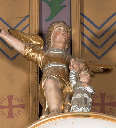 Zdjęcie nr 10: Nastawa architektoniczna, jednoosiowa, jednokondygnacyjna ze zwieńczeniem, ustawiona na dwustrefowym cokole, w górnej części z wyłamanymi pod kątem dwoma prostopadłościanami. Ołtarz drewniany, prostopadłościenny, skrzyniowy, z drewnianą mensą. Antepedium ujęte profilowaną ramą, w polu dwie, duże, płaskorzeźbione rozety na pomarańczowym tle. Nastawa ujęta parą kolumn ustawionych na tle pilastrów, dźwigających pełne belkowanie, wyłamane pod kątem na ich osi, częściowo przerwane nad polem środkowym, oraz fragmenty przerwanego półkolistego przyczółka z puttami. Pole centralne w całości wypełnione wnęką w formie stojącego prostokąta zamkniętego łukiem segmentowym nadwieszonym, ujętym profilowaną ramą, z wpisanym krucyfiksem na tle malowanych obłoków. Nad nim akantowo-wstęgowy kartusz, z napisem „OJCZE! / odpuść im / bo niewiedzą / co czynią”. Kondygnację flankują figury Matki Boskiej i św. Jana ustawione na wysuniętych krawędziach cokołu oraz uszy utworzone z suchego akantu i wstęgi. Zwieńczenie w formie zbliżonej do trapezu zamkniętego fragmentem gzymsu o kształcie łuku segmentowego z uskokiem, flankowanego spływami wolutowymi. W polu obraz Piety w formie stojącego owalu, ujęty profilowaną ramą, u góry dekorowany zwisami kwiatowymi, u dołu liśćmi. Całość zakończona figurą Anioła Stróża. Struktura polichromowana w kolorze białym; kolumny, profile i ornamentyka złocone, detal srebrzony. 