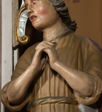 Zdjęcie nr 14: Nastawa architektoniczna, jednoosiowa, jednokondygnacyjna ze zwieńczeniem, ustawiona na dwustrefowym cokole, w górnej części z wyłamanymi pod kątem dwoma prostopadłościanami. Ołtarz drewniany, prostopadłościenny, skrzyniowy, z drewnianą mensą. Antepedium ujęte profilowaną ramą, w polu dwie, duże, płaskorzeźbione rozety na pomarańczowym tle. Nastawa ujęta parą kolumn ustawionych na tle pilastrów, dźwigających pełne belkowanie, wyłamane pod kątem na ich osi, częściowo przerwane nad polem środkowym, oraz fragmenty przerwanego półkolistego przyczółka z puttami. Pole centralne w całości wypełnione wnęką w formie stojącego prostokąta zamkniętego łukiem segmentowym nadwieszonym, ujętym profilowaną ramą, z wpisanym krucyfiksem na tle malowanych obłoków. Nad nim akantowo-wstęgowy kartusz, z napisem „OJCZE! / odpuść im / bo niewiedzą / co czynią”. Kondygnację flankują figury Matki Boskiej i św. Jana ustawione na wysuniętych krawędziach cokołu oraz uszy utworzone z suchego akantu i wstęgi. Zwieńczenie w formie zbliżonej do trapezu zamkniętego fragmentem gzymsu o kształcie łuku segmentowego z uskokiem, flankowanego spływami wolutowymi. W polu obraz Piety w formie stojącego owalu, ujęty profilowaną ramą, u góry dekorowany zwisami kwiatowymi, u dołu liśćmi. Całość zakończona figurą Anioła Stróża. Struktura polichromowana w kolorze białym; kolumny, profile i ornamentyka złocone, detal srebrzony. 