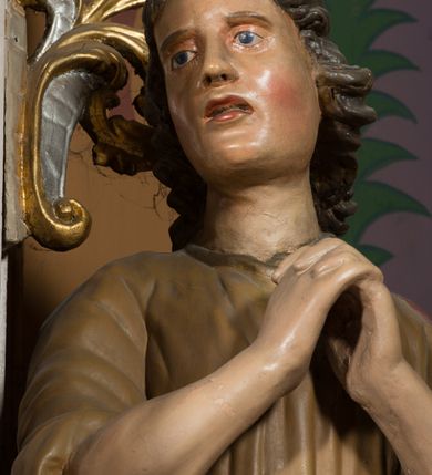 Zdjęcie nr 15: Nastawa architektoniczna, jednoosiowa, jednokondygnacyjna ze zwieńczeniem, ustawiona na dwustrefowym cokole, w górnej części z wyłamanymi pod kątem dwoma prostopadłościanami. Ołtarz drewniany, prostopadłościenny, skrzyniowy, z drewnianą mensą. Antepedium ujęte profilowaną ramą, w polu dwie, duże, płaskorzeźbione rozety na pomarańczowym tle. Nastawa ujęta parą kolumn ustawionych na tle pilastrów, dźwigających pełne belkowanie, wyłamane pod kątem na ich osi, częściowo przerwane nad polem środkowym, oraz fragmenty przerwanego półkolistego przyczółka z puttami. Pole centralne w całości wypełnione wnęką w formie stojącego prostokąta zamkniętego łukiem segmentowym nadwieszonym, ujętym profilowaną ramą, z wpisanym krucyfiksem na tle malowanych obłoków. Nad nim akantowo-wstęgowy kartusz, z napisem „OJCZE! / odpuść im / bo niewiedzą / co czynią”. Kondygnację flankują figury Matki Boskiej i św. Jana ustawione na wysuniętych krawędziach cokołu oraz uszy utworzone z suchego akantu i wstęgi. Zwieńczenie w formie zbliżonej do trapezu zamkniętego fragmentem gzymsu o kształcie łuku segmentowego z uskokiem, flankowanego spływami wolutowymi. W polu obraz Piety w formie stojącego owalu, ujęty profilowaną ramą, u góry dekorowany zwisami kwiatowymi, u dołu liśćmi. Całość zakończona figurą Anioła Stróża. Struktura polichromowana w kolorze białym; kolumny, profile i ornamentyka złocone, detal srebrzony. 