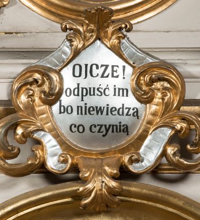 Zdjęcie nr 7: Nastawa architektoniczna, jednoosiowa, jednokondygnacyjna ze zwieńczeniem, ustawiona na dwustrefowym cokole, w górnej części z wyłamanymi pod kątem dwoma prostopadłościanami. Ołtarz drewniany, prostopadłościenny, skrzyniowy, z drewnianą mensą. Antepedium ujęte profilowaną ramą, w polu dwie, duże, płaskorzeźbione rozety na pomarańczowym tle. Nastawa ujęta parą kolumn ustawionych na tle pilastrów, dźwigających pełne belkowanie, wyłamane pod kątem na ich osi, częściowo przerwane nad polem środkowym, oraz fragmenty przerwanego półkolistego przyczółka z puttami. Pole centralne w całości wypełnione wnęką w formie stojącego prostokąta zamkniętego łukiem segmentowym nadwieszonym, ujętym profilowaną ramą, z wpisanym krucyfiksem na tle malowanych obłoków. Nad nim akantowo-wstęgowy kartusz, z napisem „OJCZE! / odpuść im / bo niewiedzą / co czynią”. Kondygnację flankują figury Matki Boskiej i św. Jana ustawione na wysuniętych krawędziach cokołu oraz uszy utworzone z suchego akantu i wstęgi. Zwieńczenie w formie zbliżonej do trapezu zamkniętego fragmentem gzymsu o kształcie łuku segmentowego z uskokiem, flankowanego spływami wolutowymi. W polu obraz Piety w formie stojącego owalu, ujęty profilowaną ramą, u góry dekorowany zwisami kwiatowymi, u dołu liśćmi. Całość zakończona figurą Anioła Stróża. Struktura polichromowana w kolorze białym; kolumny, profile i ornamentyka złocone, detal srebrzony. 