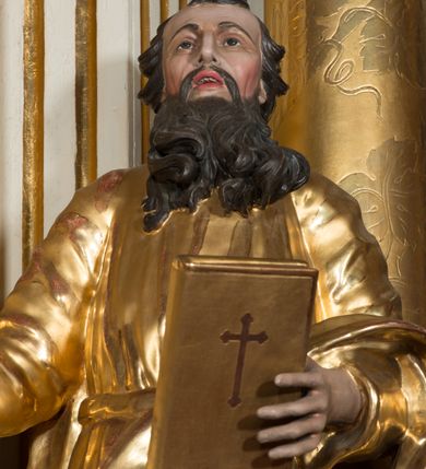 Zdjęcie nr 7: Rzeźba wydrążona z tyłu, ustawiona na nieregularnej podstawie. Święty ukazany frontalnie, w kontrapoście, w prawej, wyciągniętej w bok ręce trzyma miecz zwrócony ostrzem w dół, w lewej, ugiętej, trzyma księgę. Twarz ma szczupłą, kwadratową, o starczych rysach, migdałowatych oczach, garbatym nosie i otwartych ustach z widoczną linią zębów. Twarz ma okoloną długą, silnie kręconą brodą oraz krótkimi, falowanymi włosami. Ubrany jest w złoconą tunikę, przepasaną w talii oraz złocony płaszcz zarzucony na lewe przedramię i bok. Polichromia ciała naturalistyczna, włosy i broda ciemnobrązowe. 

