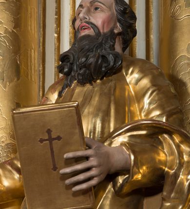 Zdjęcie nr 4: Rzeźba wydrążona z tyłu, ustawiona na nieregularnej podstawie. Święty ukazany frontalnie, w kontrapoście, w prawej, wyciągniętej w bok ręce trzyma miecz zwrócony ostrzem w dół, w lewej, ugiętej, trzyma księgę. Twarz ma szczupłą, kwadratową, o starczych rysach, migdałowatych oczach, garbatym nosie i otwartych ustach z widoczną linią zębów. Twarz ma okoloną długą, silnie kręconą brodą oraz krótkimi, falowanymi włosami. Ubrany jest w złoconą tunikę, przepasaną w talii oraz złocony płaszcz zarzucony na lewe przedramię i bok. Polichromia ciała naturalistyczna, włosy i broda ciemnobrązowe. 

