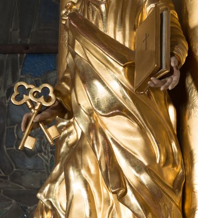 Zdjęcie nr 2: Figura drążona z tyłu, ustawiona na nieregularnej podstawie. Święty ukazany frontalnie, z uniesioną głową, prawą nogą opartą na wzniesieniu i rękami rozłożonymi na boki. W prawej dłoni trzyma dwa skrzyżowane klucze, lewą podtrzymuje zamkniętą księgę. Twarz ma szczupłą, pociągłą, o głęboko osadzonych oczach, skierowanych w górę, garbatym nosie i otwartych ustach z widoczną linią zębów. Twarz okolona krótką, falowaną brodą oraz krótkimi włosami, z łysiną na głowie. Ubrany jest w luźną, złoconą tunikę oraz zawiązany diagonalnie na prawym ramieniu złocony płaszcz. Polichromia naturalistyczna w partiach ciała, włosy siwo-brązowe. 

