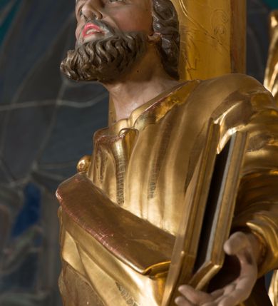 Zdjęcie nr 6: Figura drążona z tyłu, ustawiona na nieregularnej podstawie. Święty ukazany frontalnie, z uniesioną głową, prawą nogą opartą na wzniesieniu i rękami rozłożonymi na boki. W prawej dłoni trzyma dwa skrzyżowane klucze, lewą podtrzymuje zamkniętą księgę. Twarz ma szczupłą, pociągłą, o głęboko osadzonych oczach, skierowanych w górę, garbatym nosie i otwartych ustach z widoczną linią zębów. Twarz okolona krótką, falowaną brodą oraz krótkimi włosami, z łysiną na głowie. Ubrany jest w luźną, złoconą tunikę oraz zawiązany diagonalnie na prawym ramieniu złocony płaszcz. Polichromia naturalistyczna w partiach ciała, włosy siwo-brązowe. 

