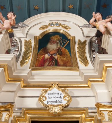 Zdjęcie nr 6: Nastawa architektoniczna, jednoosiowa, jednokondygnacyjna ze zwieńczeniem, ustawiona na dwustrefowym cokole, w górnej strefie z wyodrębnionymi dwoma prostopadłościanami. Ołtarz drewniany, prostopadłościenny, z drewnianą mensą. Antepedium ujęte profilowaną ramą z przedstawieniem gorejącego serca na czerwonym tle. Nastawa flankowana parą kolumn o kapitelach kompozytowych stojących na tle zwielokrotnionych pilastrów. Kolumny wspierają belkowanie wyłamane na ich osi oraz fragmenty falistego, przerwanego przyczółka z siedzącymi puttami. Pośrodku belkowania kartusz ujęty wieńcem laurowym z napisem „Umiłował go / Pan i chwałą / przyozdobił”. Całe pole główne wypełnione wnęką w formie stojącego prostokąta o wciętych górnych narożach, ujętego profilowaną ramą, z obrazem Najświętszego Serca Jezusa. Kondygnacja flankowana niewielkimi uszami utworzonymi ze stylizowanego akantu i wstęgi. Zwieńczenie w formie zbliżonej do kwadratu, o wklęsłych bokach dekorowanych ornamentem roślinnym, zamkniętego fragmentem gzymsu o kształcie łuku półkolistego nadwieszonego. W polu obraz św. Wojciecha o tej samej formie, w profilowanej ramie. Obraz ujęty z trzech stron ornamentem roślinnym. Nastawa flankowana figurami św. Szymona i św. Judy Tadeusza ustawionymi na wspornikach przy ścianie. Struktura polichromowana w kolorze białym, kolumny, profile złocone; ornamentyka złocona i srebrzona. 

