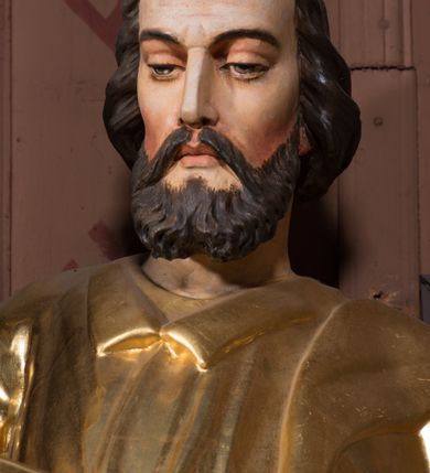 Zdjęcie nr 2: Figura pełnoplastyczna, ustawiona na nieregularnej podstawie. Święty ukazany frontalnie, z lekko pochyloną głową. W prawej, ugiętej ręce trzyma zamkniętą księgę, w lewej pałkę. Twarz ma pociągłą, o dojrzałych rysach, zmarszczonym czole, półprzymkniętych oczach, prostym nosie i pełnych ustach, okoloną krótką, falistą brodą i włosami. Ubrany jest w złoconą tunikę z kołnierzykiem, przepasaną w talii, przylegającą do ciała, silnie drapowaną oraz płaszcz zarzucony na prawe ramię postaci i opadający po bokach. Polichromia ciała naturalistyczna, włosy brązowe. 


