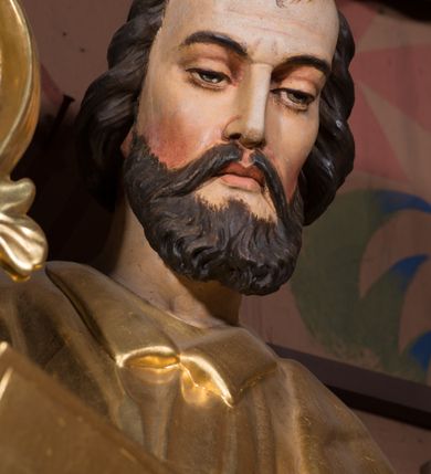 Zdjęcie nr 3: Figura pełnoplastyczna, ustawiona na nieregularnej podstawie. Święty ukazany frontalnie, z lekko pochyloną głową. W prawej, ugiętej ręce trzyma zamkniętą księgę, w lewej pałkę. Twarz ma pociągłą, o dojrzałych rysach, zmarszczonym czole, półprzymkniętych oczach, prostym nosie i pełnych ustach, okoloną krótką, falistą brodą i włosami. Ubrany jest w złoconą tunikę z kołnierzykiem, przepasaną w talii, przylegającą do ciała, silnie drapowaną oraz płaszcz zarzucony na prawe ramię postaci i opadający po bokach. Polichromia ciała naturalistyczna, włosy brązowe. 

