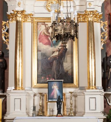 Zdjęcie nr 1: Nastawa architektoniczna, jednoosiowa, jednokondygnacyjna ze zwieńczeniem, ustawiona na dwustrefowym cokole, w górnej strefie z wyodrębnionymi dwoma prostopadłościanami. Ołtarz drewniany, prostopadłościenny, z drewnianą mensą. Antepedium ujęte profilowaną ramą z godłem franciszkanów (krzyż między skrzyżowanymi dłońmi) na czerwonym tle. Nastawa flankowana parą kolumn o kapitelach kompozytowych stojących na tle zwielokrotnionych pilastrów. Kolumny wspierają belkowanie wyłamane na ich osi oraz fragmenty falistego, przerwanego przyczółka z siedzącymi puttami. Pośrodku belkowania kartusz ujęty wieńcem laurowym z napisem „O Boże najczystsza / miłości! rozgrzej mię, / straw mię. S(więty) Aug(ustyn)”. Całe pole główne wypełnione wnęką w formie stojącego prostokąta, ujętego profilowaną ramą, z obrazem przedstawiającym św. Franciszka przed Chrystusem i Marią. Kondygnacja flankowana niewielkimi uszami utworzonymi ze stylizowanego akantu i wstęgi. Zwieńczenie w formie zbliżonej do kwadratu, o wklęsłych bokach dekorowanych ornamentem roślinnym, zamkniętego fragmentem gzymsu o kształcie łuku półkolistego nadwieszonego. W polu obraz św. Marii Magdaleny o tej samej formie, w profilowanej ramie. Obraz ujęty z trzech stron zwisami roślinnymi. Nastawa flankowana figurami św. Franciszka i św. Antoniego Padewskiego ustawionymi na wspornikach przy ścianie. Struktura polichromowana w kolorze białym, kolumny, profile złocone; ornamentyka złocona i srebrzona. 


