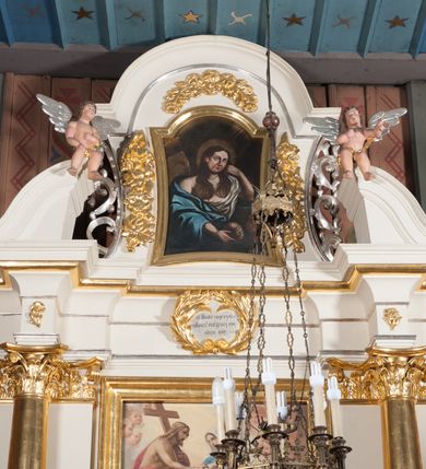 Zdjęcie nr 5: Nastawa architektoniczna, jednoosiowa, jednokondygnacyjna ze zwieńczeniem, ustawiona na dwustrefowym cokole, w górnej strefie z wyodrębnionymi dwoma prostopadłościanami. Ołtarz drewniany, prostopadłościenny, z drewnianą mensą. Antepedium ujęte profilowaną ramą z godłem franciszkanów (krzyż między skrzyżowanymi dłońmi) na czerwonym tle. Nastawa flankowana parą kolumn o kapitelach kompozytowych stojących na tle zwielokrotnionych pilastrów. Kolumny wspierają belkowanie wyłamane na ich osi oraz fragmenty falistego, przerwanego przyczółka z siedzącymi puttami. Pośrodku belkowania kartusz ujęty wieńcem laurowym z napisem „O Boże najczystsza / miłości! rozgrzej mię, / straw mię. S(więty) Aug(ustyn)”. Całe pole główne wypełnione wnęką w formie stojącego prostokąta, ujętego profilowaną ramą, z obrazem przedstawiającym św. Franciszka przed Chrystusem i Marią. Kondygnacja flankowana niewielkimi uszami utworzonymi ze stylizowanego akantu i wstęgi. Zwieńczenie w formie zbliżonej do kwadratu, o wklęsłych bokach dekorowanych ornamentem roślinnym, zamkniętego fragmentem gzymsu o kształcie łuku półkolistego nadwieszonego. W polu obraz św. Marii Magdaleny o tej samej formie, w profilowanej ramie. Obraz ujęty z trzech stron zwisami roślinnymi. Nastawa flankowana figurami św. Franciszka i św. Antoniego Padewskiego ustawionymi na wspornikach przy ścianie. Struktura polichromowana w kolorze białym, kolumny, profile złocone; ornamentyka złocona i srebrzona. 


