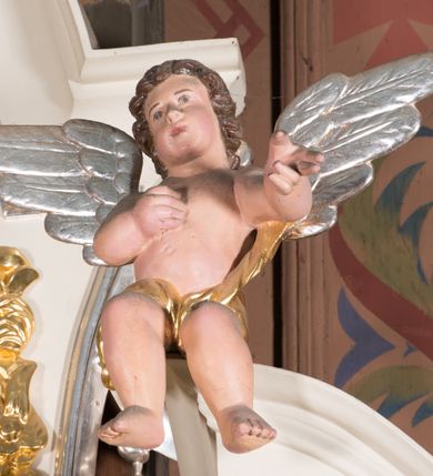 Zdjęcie nr 9: Nastawa architektoniczna, jednoosiowa, jednokondygnacyjna ze zwieńczeniem, ustawiona na dwustrefowym cokole, w górnej strefie z wyodrębnionymi dwoma prostopadłościanami. Ołtarz drewniany, prostopadłościenny, z drewnianą mensą. Antepedium ujęte profilowaną ramą z godłem franciszkanów (krzyż między skrzyżowanymi dłońmi) na czerwonym tle. Nastawa flankowana parą kolumn o kapitelach kompozytowych stojących na tle zwielokrotnionych pilastrów. Kolumny wspierają belkowanie wyłamane na ich osi oraz fragmenty falistego, przerwanego przyczółka z siedzącymi puttami. Pośrodku belkowania kartusz ujęty wieńcem laurowym z napisem „O Boże najczystsza / miłości! rozgrzej mię, / straw mię. S(więty) Aug(ustyn)”. Całe pole główne wypełnione wnęką w formie stojącego prostokąta, ujętego profilowaną ramą, z obrazem przedstawiającym św. Franciszka przed Chrystusem i Marią. Kondygnacja flankowana niewielkimi uszami utworzonymi ze stylizowanego akantu i wstęgi. Zwieńczenie w formie zbliżonej do kwadratu, o wklęsłych bokach dekorowanych ornamentem roślinnym, zamkniętego fragmentem gzymsu o kształcie łuku półkolistego nadwieszonego. W polu obraz św. Marii Magdaleny o tej samej formie, w profilowanej ramie. Obraz ujęty z trzech stron zwisami roślinnymi. Nastawa flankowana figurami św. Franciszka i św. Antoniego Padewskiego ustawionymi na wspornikach przy ścianie. Struktura polichromowana w kolorze białym, kolumny, profile złocone; ornamentyka złocona i srebrzona. 


