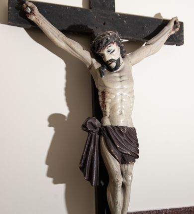 Zdjęcie nr 2: Rzeźba Chrystusa przybita do krzyża trzema gwoździami, pełna. Zbawiciel ukazany w typie Cristo vivo, w lekkim zwisie, z głową pochyloną na prawą stronę. Chrystus ma szczupłą sylwetkę ciała, delikatnie podkreśloną linię żeber. Jego twarz jest podłużna, ma długi nos, delikatnie otwarte usta i oczy, krótką brodę. Ma długie, brązowe włosy spływające na plecy i prawe ramię, a na głowie założoną koronę cierniową złożoną z dwóch gałązek. Biodra oplata brązowe perizonium, zawiązane na prawym boku z jednym końcem zwisającym wzdłuż prawego uda. Z dłoni, stóp i boku Chrystusa spływają strużki krwi. Polichromia ciała naturalistyczna, krzyż brązowy. 