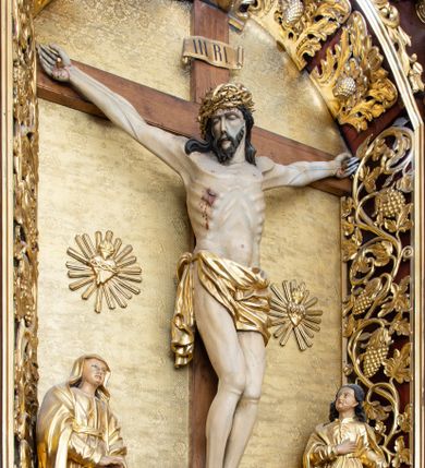 Zdjęcie nr 1: Rzeźba Chrystusa przybita do krzyża trzema gwoździami. Chrystus ukazany w typie Cristo morte, w lekkim zwisie, z głową pochyloną na prawą stronę. Ma szczupłą sylwetkę ciała, podkreśloną linię żeber i mostka. Jego twarz jest podłużna, ma długi nos, otwarte usta i zamknięte oczy oraz krótką brodę. Włosy długie, ciemnobrązowe, spływają falami do przodu i na plecy. Na głowie ma założoną szeroką, złoconą koronę cierniową. Jego biodra oplata złocone perizonium, zawiązane na prawym boku ze zwisem wzdłuż prawego uda. Z dłoni, stóp i boku Chrystusa spływają strużki krwi. Nad głową wisi titulus w formie poziomej banderoli z napisem „I. N. R. I.”. Krzyż prosty, gładki, malowany na brązowo. Polichromia ciała naturalistyczna; perizonium, korona i titulus złocone.





