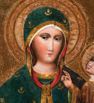 Zdjęcie nr 9: Obraz w kształcie stojącego prostokąta. W centrum kompozycji Matka Boska w typie Hodegetrii ukazana w półpostaci, frontalnie z Dzieciątkiem Jezus na lewym reku, prawą na nie wskazująca. Twarz Marii pociągła, z długim nosem, małymi ustami, ciemnobrązowymi oczami o ciemnej karnacji z zarumienionymi policzkami. Matka Boska ubrana jest w czerwoną suknię ze złotą lamówką przy szyi oraz niebieski płaszcz z motywami kwiatowymi i złotą lamówką na brzegu, zarzucony na ramiona i głowę, zawiązany na piersi wstążką w kokardkę. Dzieciątko ukazane w całej postaci, zwrócone trzy czwarte w prawo, lewą ręką podtrzymuje złotą księgę, prawą unosi na wysokości piersi w geście błogosławieństwa. Twarz okrągła z długim nosem, wąskimi ustami, półprzymkniętymi oczami, okolona krótkimi i brązowymi włosami. Jezus ubrany jest w szarą suknię z długimi rękawami, zdobioną żółto-niebieskim ornamentem kwiatowym oraz złote sandały. Głowy obu postaci ujmują złocone promieniste nimby, otoczone złotym okręgiem. Na głowie Marii i Dzieciątka złote korony: korona Dzieciątka zamknięta, korona Marii widoczna do połowy. Tło złote, ryte w ornamenty roślinne. Rama podwójna: wewnętrzna złocona i profilowana, a zewnętrzna ozdobiona rzeźbioną dekoracją roślinną na czerwonym tle, na brzegach złocona i profilowana.