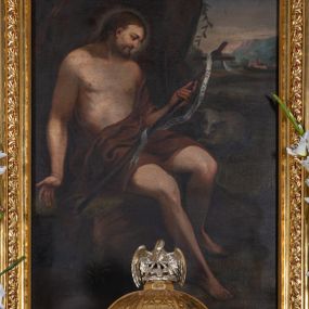 Zdjęcie nr 1: Obraz w kształcie stojącego prostokąta zamkniętego łukiem półkolistym z przedstawieniem św. Jana Chrzciciela. W centrum kompozycji ukazany święty siedzący na skale, zwrócony trzy czwarte w lewo, z prawą stopą wysuniętą do przodu, w lewej ręce trzyma krzyż, a prawą ma odwiedzioną na bok, głowę zwraca w lewą stronę, w kierunku krzyża. Twarz widoczna z prawego profilu, okolona krótką brodą, ze spiczastym nosem; włosy długie, ciemnobrązowe, opadające na plecy. Święty ubrany jest 
 w brązową szatę odsłaniającą nagi tors i nogi. Krzyż długi, opleciony białą banderolą z napisem „ECCE AGNUS DEI”. Po lewej stronie świętego siedzi baranek. W oddali, po prawej stronie obrazu widoczne miasto i pejzaż górski, nad świętym wysoka brązowa skała. Obraz umieszczony jest w złoconej, drewnianej ramie, zdobionej rzędem stylizowanych listków akantu na czerwonym tle.




