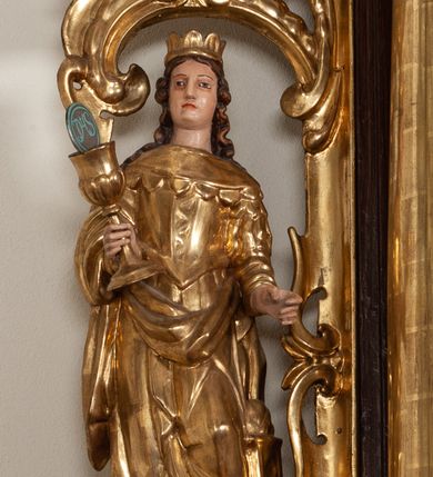 Zdjęcie nr 19: Ołtarz architektoniczny, dwukondygnacyjny, jednoosiowy ze zwieńczeniem. Mensa prostopadłościenna, antepedium w kształcie leżącego prostokąta, flankowane dwoma kanelowanymi pilastrami. W polu, w złoconej ramie dwie połączone płyciny w kształcie stojącego prostokąta wypełnione symetryczną dekoracją z akantu na błękitnym tle. Tabernakulum w formie prostopadłościennej, marmurowej skrzynki, zamknięte od góry prostym, złoconym gzymsem. Ścianka frontowa i drzwiczki obwiedzione złoconymi listwami, w polu łaciński krzyż. Cokół nastawy ustawiony na jednym stopniu, pośrodku zdobiony płyciną w kształcie leżącego prostokąta o zaokrąglonych krótszych bokach, imposty dekorowane mniejszymi płycinami wypełnionymi dekoracją roślinną. Pierwsza kondygnacja ujęta parą kolumn dźwigających przerwane belkowanie z przyczółkami, po bokach dodatkowo flankowana uszami wykończonymi ornamentem małżowinowo-chrząstkowym. W polu głównym obraz Matki Boskiej Szkaplerznej oraz św. Józefa z Dzieciątkiem i ze św. Janem Chrzcicielem na zasuwie, nad nimi para, małych uskrzydlonych aniołków. Po bokach nastawy dwie rzeźby: po prawej św. Katarzyna Aleksandryjska, a po lewej św. Barbara. Na przyczółkach usadzone dwie rzeźby aniołów z rozłożonymi szeroko rękami. Kolumny ustawione na tle prostokątnych płycin, z bazami, trzony gładkie, kapitele kompozytowe. Druga kondygnacja flankowana parą kolumn podtrzymujących wyłamane belkowanie. W polu, w ramie o kształcie stojącego prostokąta o ściętych narożach obraz św. Katarzyny Aleksandryjskiej. W zwieńczeniu promienista gloria z monogramem Marii na błękitnym tle, obwiedzionym wieńcem z obłoków. Struktura malowana w kolorze naturalnego drewna, ornamentyka złocona, detale srebrzone i błękitne.

