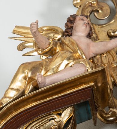 Zdjęcie nr 23: Ołtarz architektoniczny, dwukondygnacyjny, jednoosiowy ze zwieńczeniem. Mensa prostopadłościenna, antepedium w kształcie leżącego prostokąta, flankowane dwoma kanelowanymi pilastrami. W polu, w złoconej ramie dwie połączone płyciny w kształcie stojącego prostokąta wypełnione symetryczną dekoracją z akantu na błękitnym tle. Tabernakulum w formie prostopadłościennej, marmurowej skrzynki, zamknięte od góry prostym, złoconym gzymsem. Ścianka frontowa i drzwiczki obwiedzione złoconymi listwami, w polu łaciński krzyż. Cokół nastawy ustawiony na jednym stopniu, pośrodku zdobiony płyciną w kształcie leżącego prostokąta o zaokrąglonych krótszych bokach, imposty dekorowane mniejszymi płycinami wypełnionymi dekoracją roślinną. Pierwsza kondygnacja ujęta parą kolumn dźwigających przerwane belkowanie z przyczółkami, po bokach dodatkowo flankowana uszami wykończonymi ornamentem małżowinowo-chrząstkowym. W polu głównym obraz Matki Boskiej Szkaplerznej oraz św. Józefa z Dzieciątkiem i ze św. Janem Chrzcicielem na zasuwie, nad nimi para, małych uskrzydlonych aniołków. Po bokach nastawy dwie rzeźby: po prawej św. Katarzyna Aleksandryjska, a po lewej św. Barbara. Na przyczółkach usadzone dwie rzeźby aniołów z rozłożonymi szeroko rękami. Kolumny ustawione na tle prostokątnych płycin, z bazami, trzony gładkie, kapitele kompozytowe. Druga kondygnacja flankowana parą kolumn podtrzymujących wyłamane belkowanie. W polu, w ramie o kształcie stojącego prostokąta o ściętych narożach obraz św. Katarzyny Aleksandryjskiej. W zwieńczeniu promienista gloria z monogramem Marii na błękitnym tle, obwiedzionym wieńcem z obłoków. Struktura malowana w kolorze naturalnego drewna, ornamentyka złocona, detale srebrzone i błękitne.

