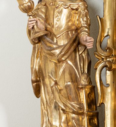 Zdjęcie nr 22: Ołtarz architektoniczny, dwukondygnacyjny, jednoosiowy ze zwieńczeniem. Mensa prostopadłościenna, antepedium w kształcie leżącego prostokąta, flankowane dwoma kanelowanymi pilastrami. W polu, w złoconej ramie dwie połączone płyciny w kształcie stojącego prostokąta wypełnione symetryczną dekoracją z akantu na błękitnym tle. Tabernakulum w formie prostopadłościennej, marmurowej skrzynki, zamknięte od góry prostym, złoconym gzymsem. Ścianka frontowa i drzwiczki obwiedzione złoconymi listwami, w polu łaciński krzyż. Cokół nastawy ustawiony na jednym stopniu, pośrodku zdobiony płyciną w kształcie leżącego prostokąta o zaokrąglonych krótszych bokach, imposty dekorowane mniejszymi płycinami wypełnionymi dekoracją roślinną. Pierwsza kondygnacja ujęta parą kolumn dźwigających przerwane belkowanie z przyczółkami, po bokach dodatkowo flankowana uszami wykończonymi ornamentem małżowinowo-chrząstkowym. W polu głównym obraz Matki Boskiej Szkaplerznej oraz św. Józefa z Dzieciątkiem i ze św. Janem Chrzcicielem na zasuwie, nad nimi para, małych uskrzydlonych aniołków. Po bokach nastawy dwie rzeźby: po prawej św. Katarzyna Aleksandryjska, a po lewej św. Barbara. Na przyczółkach usadzone dwie rzeźby aniołów z rozłożonymi szeroko rękami. Kolumny ustawione na tle prostokątnych płycin, z bazami, trzony gładkie, kapitele kompozytowe. Druga kondygnacja flankowana parą kolumn podtrzymujących wyłamane belkowanie. W polu, w ramie o kształcie stojącego prostokąta o ściętych narożach obraz św. Katarzyny Aleksandryjskiej. W zwieńczeniu promienista gloria z monogramem Marii na błękitnym tle, obwiedzionym wieńcem z obłoków. Struktura malowana w kolorze naturalnego drewna, ornamentyka złocona, detale srebrzone i błękitne.

