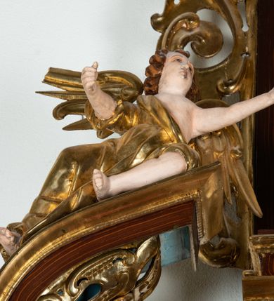 Zdjęcie nr 37: Ołtarz architektoniczny, dwukondygnacyjny, jednoosiowy ze zwieńczeniem. Mensa prostopadłościenna, antepedium w kształcie leżącego prostokąta, flankowane dwoma kanelowanymi pilastrami. W polu, w złoconej ramie dwie połączone płyciny w kształcie stojącego prostokąta wypełnione symetryczną dekoracją z akantu na błękitnym tle. Tabernakulum w formie prostopadłościennej, marmurowej skrzynki, zamknięte od góry prostym, złoconym gzymsem. Ścianka frontowa i drzwiczki obwiedzione złoconymi listwami, w polu łaciński krzyż. Cokół nastawy ustawiony na jednym stopniu, pośrodku zdobiony płyciną w kształcie leżącego prostokąta o zaokrąglonych krótszych bokach, imposty dekorowane mniejszymi płycinami wypełnionymi dekoracją roślinną. Pierwsza kondygnacja ujęta parą kolumn dźwigających przerwane belkowanie z przyczółkami, po bokach dodatkowo flankowana uszami wykończonymi ornamentem małżowinowo-chrząstkowym. W polu głównym obraz Matki Boskiej Szkaplerznej oraz św. Józefa z Dzieciątkiem i ze św. Janem Chrzcicielem na zasuwie, nad nimi para, małych uskrzydlonych aniołków. Po bokach nastawy dwie rzeźby: po prawej św. Katarzyna Aleksandryjska, a po lewej św. Barbara. Na przyczółkach usadzone dwie rzeźby aniołów z rozłożonymi szeroko rękami. Kolumny ustawione na tle prostokątnych płycin, z bazami, trzony gładkie, kapitele kompozytowe. Druga kondygnacja flankowana parą kolumn podtrzymujących wyłamane belkowanie. W polu, w ramie o kształcie stojącego prostokąta o ściętych narożach obraz św. Katarzyny Aleksandryjskiej. W zwieńczeniu promienista gloria z monogramem Marii na błękitnym tle, obwiedzionym wieńcem z obłoków. Struktura malowana w kolorze naturalnego drewna, ornamentyka złocona, detale srebrzone i błękitne.

