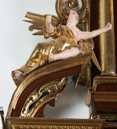 Zdjęcie nr 41: Ołtarz architektoniczny, dwukondygnacyjny, jednoosiowy ze zwieńczeniem. Mensa prostopadłościenna, antepedium w kształcie leżącego prostokąta, flankowane dwoma kanelowanymi pilastrami. W polu, w złoconej ramie dwie połączone płyciny w kształcie stojącego prostokąta wypełnione symetryczną dekoracją z akantu na błękitnym tle. Tabernakulum w formie prostopadłościennej, marmurowej skrzynki, zamknięte od góry prostym, złoconym gzymsem. Ścianka frontowa i drzwiczki obwiedzione złoconymi listwami, w polu łaciński krzyż. Cokół nastawy ustawiony na jednym stopniu, pośrodku zdobiony płyciną w kształcie leżącego prostokąta o zaokrąglonych krótszych bokach, imposty dekorowane mniejszymi płycinami wypełnionymi dekoracją roślinną. Pierwsza kondygnacja ujęta parą kolumn dźwigających przerwane belkowanie z przyczółkami, po bokach dodatkowo flankowana uszami wykończonymi ornamentem małżowinowo-chrząstkowym. W polu głównym obraz Matki Boskiej Szkaplerznej oraz św. Józefa z Dzieciątkiem i ze św. Janem Chrzcicielem na zasuwie, nad nimi para, małych uskrzydlonych aniołków. Po bokach nastawy dwie rzeźby: po prawej św. Katarzyna Aleksandryjska, a po lewej św. Barbara. Na przyczółkach usadzone dwie rzeźby aniołów z rozłożonymi szeroko rękami. Kolumny ustawione na tle prostokątnych płycin, z bazami, trzony gładkie, kapitele kompozytowe. Druga kondygnacja flankowana parą kolumn podtrzymujących wyłamane belkowanie. W polu, w ramie o kształcie stojącego prostokąta o ściętych narożach obraz św. Katarzyny Aleksandryjskiej. W zwieńczeniu promienista gloria z monogramem Marii na błękitnym tle, obwiedzionym wieńcem z obłoków. Struktura malowana w kolorze naturalnego drewna, ornamentyka złocona, detale srebrzone i błękitne.

