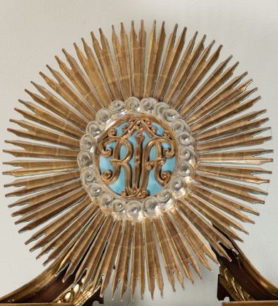 Zdjęcie nr 54: Ołtarz architektoniczny, dwukondygnacyjny, jednoosiowy ze zwieńczeniem. Mensa prostopadłościenna, antepedium w kształcie leżącego prostokąta, flankowane dwoma kanelowanymi pilastrami. W polu, w złoconej ramie dwie połączone płyciny w kształcie stojącego prostokąta wypełnione symetryczną dekoracją z akantu na błękitnym tle. Tabernakulum w formie prostopadłościennej, marmurowej skrzynki, zamknięte od góry prostym, złoconym gzymsem. Ścianka frontowa i drzwiczki obwiedzione złoconymi listwami, w polu łaciński krzyż. Cokół nastawy ustawiony na jednym stopniu, pośrodku zdobiony płyciną w kształcie leżącego prostokąta o zaokrąglonych krótszych bokach, imposty dekorowane mniejszymi płycinami wypełnionymi dekoracją roślinną. Pierwsza kondygnacja ujęta parą kolumn dźwigających przerwane belkowanie z przyczółkami, po bokach dodatkowo flankowana uszami wykończonymi ornamentem małżowinowo-chrząstkowym. W polu głównym obraz Matki Boskiej Szkaplerznej oraz św. Józefa z Dzieciątkiem i ze św. Janem Chrzcicielem na zasuwie, nad nimi para, małych uskrzydlonych aniołków. Po bokach nastawy dwie rzeźby: po prawej św. Katarzyna Aleksandryjska, a po lewej św. Barbara. Na przyczółkach usadzone dwie rzeźby aniołów z rozłożonymi szeroko rękami. Kolumny ustawione na tle prostokątnych płycin, z bazami, trzony gładkie, kapitele kompozytowe. Druga kondygnacja flankowana parą kolumn podtrzymujących wyłamane belkowanie. W polu, w ramie o kształcie stojącego prostokąta o ściętych narożach obraz św. Katarzyny Aleksandryjskiej. W zwieńczeniu promienista gloria z monogramem Marii na błękitnym tle, obwiedzionym wieńcem z obłoków. Struktura malowana w kolorze naturalnego drewna, ornamentyka złocona, detale srebrzone i błękitne.

