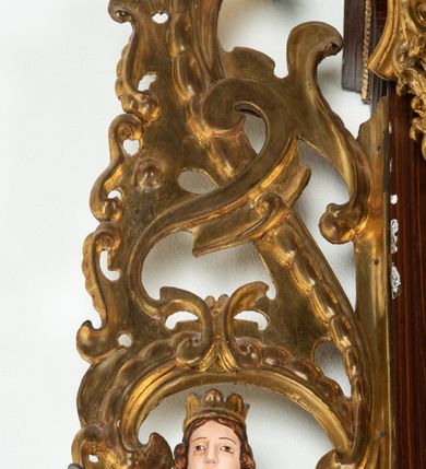 Zdjęcie nr 50: Ołtarz architektoniczny, dwukondygnacyjny, jednoosiowy ze zwieńczeniem. Mensa prostopadłościenna, antepedium w kształcie leżącego prostokąta, flankowane dwoma kanelowanymi pilastrami. W polu, w złoconej ramie dwie połączone płyciny w kształcie stojącego prostokąta wypełnione symetryczną dekoracją z akantu na błękitnym tle. Tabernakulum w formie prostopadłościennej, marmurowej skrzynki, zamknięte od góry prostym, złoconym gzymsem. Ścianka frontowa i drzwiczki obwiedzione złoconymi listwami, w polu łaciński krzyż. Cokół nastawy ustawiony na jednym stopniu, pośrodku zdobiony płyciną w kształcie leżącego prostokąta o zaokrąglonych krótszych bokach, imposty dekorowane mniejszymi płycinami wypełnionymi dekoracją roślinną. Pierwsza kondygnacja ujęta parą kolumn dźwigających przerwane belkowanie z przyczółkami, po bokach dodatkowo flankowana uszami wykończonymi ornamentem małżowinowo-chrząstkowym. W polu głównym obraz Matki Boskiej Szkaplerznej oraz św. Józefa z Dzieciątkiem i ze św. Janem Chrzcicielem na zasuwie, nad nimi para, małych uskrzydlonych aniołków. Po bokach nastawy dwie rzeźby: po prawej św. Katarzyna Aleksandryjska, a po lewej św. Barbara. Na przyczółkach usadzone dwie rzeźby aniołów z rozłożonymi szeroko rękami. Kolumny ustawione na tle prostokątnych płycin, z bazami, trzony gładkie, kapitele kompozytowe. Druga kondygnacja flankowana parą kolumn podtrzymujących wyłamane belkowanie. W polu, w ramie o kształcie stojącego prostokąta o ściętych narożach obraz św. Katarzyny Aleksandryjskiej. W zwieńczeniu promienista gloria z monogramem Marii na błękitnym tle, obwiedzionym wieńcem z obłoków. Struktura malowana w kolorze naturalnego drewna, ornamentyka złocona, detale srebrzone i błękitne.

