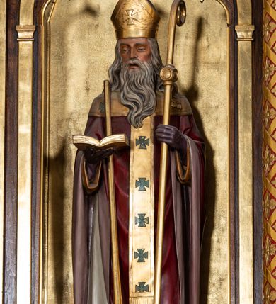 Zdjęcie nr 12: Ołtarz przyścienny, architektoniczny, trójosiowy, jednokondygnacyjny ze zwieńczeniem. Mensa prostopadłościenna. Antepedium trójosiowe, flankowane czterema kolumnami. W osi środkowej płycina w kształcie leżącego prostokąta z monogramem Matki Boskiej w polu i wieńcem z róż. W osiach bocznych płyciny w kształcie stojących prostokątów z bukietem narcyzów w polu. Tabernakulum metalowe w formie prostopadłościennej szafki zamkniętej profilowanym gzymsem wspartym na dwóch smukłych kolumnach. Drzwiczki prostokątne, zamknięte półkoliście z przedstawieniem krzyża z gorejącym sercem w czwórliściu oraz motywem winorośli i kłosów zbóż. Tron wystawienia w formie baldachimu wspartego na czterech smukłych kolumnach, zwieńczonego kopułą i rzeźbą pelikana karmiącego młode. Retabulum ustawione na wysokim cokole i predelli. Nastawa flankowana parą kolumn w części środkowej i parą pilastrów na zewnątrz. Podpory dźwigają wyłamane belkowanie, nad osią środkową wysunięte do przodu i tworzące łuk nadwieszony. W polu głównym, w ramie w kształcie stojącego prostokąta, zamkniętego łukiem półkolistym, umieszczony obraz Matki Boskiej Zembrzyckiej oraz św. Jana Chrzciciela na zasuwie. Nad polem głównym trzy uskrzydlone główki aniołków. W osiach bocznych, w niszach zamkniętych łukiem w ośli grzbiet i zwieńczonych krzyżykiem, ustawione figury świętych: po prawej św. Stanisława, po lewej św. Wojciecha. Zwieńczenie w kształcie cebulastej, ażurowej kopuły, dekorowanej ornamentem roślinnym, spiętej u góry zamkniętą koroną z krzyżykiem. Po bokach zwieńczenia, na osi pilastrów para stojących aniołów. Cokół zdobiony fryzem arkadkowym i zamknięty od góry profilowanym gzymsem. Predella pośrodku dekorowana fryzem arkadowym, a w osiach bocznych stylizowanym ornamentem roślinnym, a na skrajach zawiniętym liściem akantu. Kolumny i pilastry ustawione na bazach, kapitele kompozytowe, trzony kolumn dekorowane ukośną kratką z rozetkami w polu, a trzony pilastrów z płyciną wypełnioną wicią z róż i innych kwiatów. Po bokach ołtarz ujęty ażurowymi uszakami utworzonymi z wolutowo skręconej wici roślinnej. Fryz dekorowany rzędem rozetek. Struktura malowana w kolorze naturalnego drewna, ornamentyka i profilowania złocone, detale czerwone i bordowe, suknie aniołów srebrzone.
