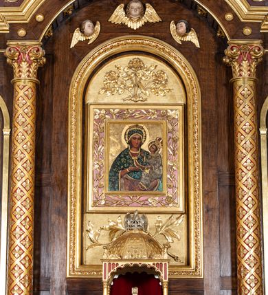 Zdjęcie nr 5: Ołtarz przyścienny, architektoniczny, trójosiowy, jednokondygnacyjny ze zwieńczeniem. Mensa prostopadłościenna. Antepedium trójosiowe, flankowane czterema kolumnami. W osi środkowej płycina w kształcie leżącego prostokąta z monogramem Matki Boskiej w polu i wieńcem z róż. W osiach bocznych płyciny w kształcie stojących prostokątów z bukietem narcyzów w polu. Tabernakulum metalowe w formie prostopadłościennej szafki zamkniętej profilowanym gzymsem wspartym na dwóch smukłych kolumnach. Drzwiczki prostokątne, zamknięte półkoliście z przedstawieniem krzyża z gorejącym sercem w czwórliściu oraz motywem winorośli i kłosów zbóż. Tron wystawienia w formie baldachimu wspartego na czterech smukłych kolumnach, zwieńczonego kopułą i rzeźbą pelikana karmiącego młode. Retabulum ustawione na wysokim cokole i predelli. Nastawa flankowana parą kolumn w części środkowej i parą pilastrów na zewnątrz. Podpory dźwigają wyłamane belkowanie, nad osią środkową wysunięte do przodu i tworzące łuk nadwieszony. W polu głównym, w ramie w kształcie stojącego prostokąta, zamkniętego łukiem półkolistym, umieszczony obraz Matki Boskiej Zembrzyckiej oraz św. Jana Chrzciciela na zasuwie. Nad polem głównym trzy uskrzydlone główki aniołków. W osiach bocznych, w niszach zamkniętych łukiem w ośli grzbiet i zwieńczonych krzyżykiem, ustawione figury świętych: po prawej św. Stanisława, po lewej św. Wojciecha. Zwieńczenie w kształcie cebulastej, ażurowej kopuły, dekorowanej ornamentem roślinnym, spiętej u góry zamkniętą koroną z krzyżykiem. Po bokach zwieńczenia, na osi pilastrów para stojących aniołów. Cokół zdobiony fryzem arkadkowym i zamknięty od góry profilowanym gzymsem. Predella pośrodku dekorowana fryzem arkadowym, a w osiach bocznych stylizowanym ornamentem roślinnym, a na skrajach zawiniętym liściem akantu. Kolumny i pilastry ustawione na bazach, kapitele kompozytowe, trzony kolumn dekorowane ukośną kratką z rozetkami w polu, a trzony pilastrów z płyciną wypełnioną wicią z róż i innych kwiatów. Po bokach ołtarz ujęty ażurowymi uszakami utworzonymi z wolutowo skręconej wici roślinnej. Fryz dekorowany rzędem rozetek. Struktura malowana w kolorze naturalnego drewna, ornamentyka i profilowania złocone, detale czerwone i bordowe, suknie aniołów srebrzone.
