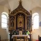 Zdjęcie nr 1: Ołtarz przyścienny, architektoniczny, trójosiowy, jednokondygnacyjny ze zwieńczeniem. Mensa prostopadłościenna. Antepedium trójosiowe, flankowane czterema kolumnami. W osi środkowej płycina w kształcie leżącego prostokąta z monogramem Matki Boskiej w polu i wieńcem z róż. W osiach bocznych płyciny w kształcie stojących prostokątów z bukietem narcyzów w polu. Tabernakulum metalowe w formie prostopadłościennej szafki zamkniętej profilowanym gzymsem wspartym na dwóch smukłych kolumnach. Drzwiczki prostokątne, zamknięte półkoliście z przedstawieniem krzyża z gorejącym sercem w czwórliściu oraz motywem winorośli i kłosów zbóż. Tron wystawienia w formie baldachimu wspartego na czterech smukłych kolumnach, zwieńczonego kopułą i rzeźbą pelikana karmiącego młode. Retabulum ustawione na wysokim cokole i predelli. Nastawa flankowana parą kolumn w części środkowej i parą pilastrów na zewnątrz. Podpory dźwigają wyłamane belkowanie, nad osią środkową wysunięte do przodu i tworzące łuk nadwieszony. W polu głównym, w ramie w kształcie stojącego prostokąta, zamkniętego łukiem półkolistym, umieszczony obraz Matki Boskiej Zembrzyckiej oraz św. Jana Chrzciciela na zasuwie. Nad polem głównym trzy uskrzydlone główki aniołków. W osiach bocznych, w niszach zamkniętych łukiem w ośli grzbiet i zwieńczonych krzyżykiem, ustawione figury świętych: po prawej św. Stanisława, po lewej św. Wojciecha. Zwieńczenie w kształcie cebulastej, ażurowej kopuły, dekorowanej ornamentem roślinnym, spiętej u góry zamkniętą koroną z krzyżykiem. Po bokach zwieńczenia, na osi pilastrów para stojących aniołów. Cokół zdobiony fryzem arkadkowym i zamknięty od góry profilowanym gzymsem. Predella pośrodku dekorowana fryzem arkadowym, a w osiach bocznych stylizowanym ornamentem roślinnym, a na skrajach zawiniętym liściem akantu. Kolumny i pilastry ustawione na bazach, kapitele kompozytowe, trzony kolumn dekorowane ukośną kratką z rozetkami w polu, a trzony pilastrów z płyciną wypełnioną wicią z róż i innych kwiatów. Po bokach ołtarz ujęty ażurowymi uszakami utworzonymi z wolutowo skręconej wici roślinnej. Fryz dekorowany rzędem rozetek. Struktura malowana w kolorze naturalnego drewna, ornamentyka i profilowania złocone, detale czerwone i bordowe, suknie aniołów srebrzone.
