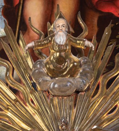 Zdjęcie nr 9: Pokrywa chrzcielnicy na planie koła z dekoracją imitującą puklowanie. Na szczycie pokrywy umieszczona rzeźbiona scena przedstawiająca Chrzest Chrystusa w Jordanie. Po lewej stronie Jezus stopami zanurzony w wodach Jordanu, zwrócony trzy czwarte w stronę św. Jana Chrzciciela, z rękami złożonymi na piersiach w geście pokory. Twarz podłużna, okolona brodą z długim nosem i wzrokiem skierowanym w dół. Włosy długie, opadające na plecy. Ubrany jest w złocone perizonium, luźno zawiązane na biodrach. Po prawej św. Jan Chrzciciel klęczący na kamiennym postumencie, zwrócony w prawo, w lewej ręce trzymający krzyż, prawą polewający wodą Chrystusa. Twarz podłużna, okolona krótką brodą i długimi włosami. Ubrany jest w skórę wielbłądzią, odsłaniającą nagi tors i nogi. Krzyż długi z napisem na banderoli: „OTO BARANEK BOŻY”. Za nimi zatknięta jest duża, promienista gloria, pośrodku której znajduje się gołębica Ducha Świętego, a nad nią półpostać Boga Ojca wynurzająca się z obłoków z rozłożonymi szeroko rękami. Bóg Ojciec o rysach twarzy starszego mężczyzny z siwymi włosami i brodą, ubrany w złoconą suknię. Polichromia w odsłoniętych partiach ciała naturalistyczna, podstawa pokrywy, gloria i szaty złocone, obłoki srebrzone.


