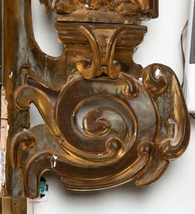 Zdjęcie nr 9: Rzeźba przedstawiająca św. Katarzynę Aleksandryjską, ustawiona na niskim cokole. Święta ukazana frontalnie w delikatnym kontrapoście, z sylwetką przechyloną w prawą stronę, z lewą ręką złożoną na tułowiu, a prawą opartą o złamane koło. Twarz owalna z małymi ustami, długim i wąskim nosem, migdałowymi oczami. Włosy długie, brązowe, opadające falami na plecy i wzdłuż ramion. Święta ubrana jest w złotą, długą suknię z długimi rękawami oraz złoty płaszcz, na stopach ma założone buty, a na głowę otwartą koronę. Polichromia w odsłoniętych partiach ciała naturalistyczna, szaty i atrybuty złocone i srebrzone, detale błękitne (wnętrze korony).



