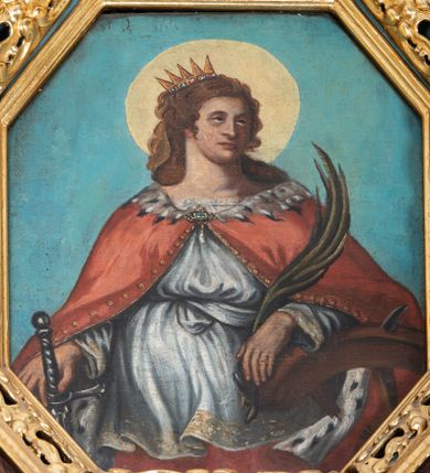 Zdjęcie nr 1: Obraz w kształcie stojącego prostokąta o ściętych narożach z przedstawieniem św. Katarzyny Aleksandryjskiej.  W centrum kompozycji ukazana św. Katarzyna w półpostaci z głową zwróconą w lewo, lewą ręką opartą na złamanym kole, w prawej dłoni trzyma miecz, a w lewej palmę męczeństwa. Ma owalną twarz z prostym nosem, okoloną długimi, brązowymi włosami, opadającymi na ramiona. Ubrana jest w czerwoną suknię, białą tunikę, zdobioną na brzegach oraz czerwony płaszcz podbity gronostajem, spięty na piersi broszą. Na głowie ma założoną otwartą koronę, a wokół niej kolisty, złoty nimb. Tło obrazu jednolite, jasnoniebieskie. Rama drewniana, złocona, zdobiona ornamentem małżowinowo-chrząstkowym.

