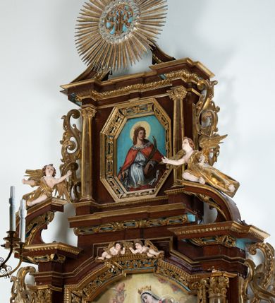 Zdjęcie nr 5: Obraz w kształcie stojącego prostokąta o ściętych narożach z przedstawieniem św. Katarzyny Aleksandryjskiej.  W centrum kompozycji ukazana św. Katarzyna w półpostaci z głową zwróconą w lewo, lewą ręką opartą na złamanym kole, w prawej dłoni trzyma miecz, a w lewej palmę męczeństwa. Ma owalną twarz z prostym nosem, okoloną długimi, brązowymi włosami, opadającymi na ramiona. Ubrana jest w czerwoną suknię, białą tunikę, zdobioną na brzegach oraz czerwony płaszcz podbity gronostajem, spięty na piersi broszą. Na głowie ma założoną otwartą koronę, a wokół niej kolisty, złoty nimb. Tło obrazu jednolite, jasnoniebieskie. Rama drewniana, złocona, zdobiona ornamentem małżowinowo-chrząstkowym.

