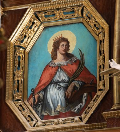 Zdjęcie nr 3: Obraz w kształcie stojącego prostokąta o ściętych narożach z przedstawieniem św. Katarzyny Aleksandryjskiej.  W centrum kompozycji ukazana św. Katarzyna w półpostaci z głową zwróconą w lewo, lewą ręką opartą na złamanym kole, w prawej dłoni trzyma miecz, a w lewej palmę męczeństwa. Ma owalną twarz z prostym nosem, okoloną długimi, brązowymi włosami, opadającymi na ramiona. Ubrana jest w czerwoną suknię, białą tunikę, zdobioną na brzegach oraz czerwony płaszcz podbity gronostajem, spięty na piersi broszą. Na głowie ma założoną otwartą koronę, a wokół niej kolisty, złoty nimb. Tło obrazu jednolite, jasnoniebieskie. Rama drewniana, złocona, zdobiona ornamentem małżowinowo-chrząstkowym.

