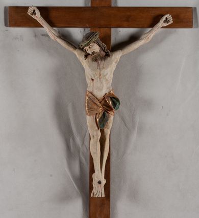 Zdjęcie nr 1: Rzeźba Chrystusa przybita do krzyża trzema gwoździami, pełna. Zbawiciel ukazany w typie Cristo morte, w lekkim zwisie, z głową pochyloną na prawą stronę. Jezus ma szczupłą sylwetkę ciała, duże stopy, delikatnie podkreśloną linię żeber. Jego twarz jest podłużna, ma długi nos, delikatnie otwarte usta i zamknięte oczy, krótką brodę, zwiniętą na końcu w dwa pukle. Ma długie, brązowe włosy spływające falami do przodu, a na głowie założoną koronę cierniową złożoną z prostych zielonych gałązek. Biodra oplata złocone perizonium z zieloną podszewką, zawiązane pośrodku. Z dłoni, stóp i boku Chrystusa spływają strużki krwi. Polichromia ciała naturalistyczna, perizonium złocone. Nad głową Jezusa titulus w formie banderoli z napisem „I. N. R. I.”. Krzyż prosty, gładki, malowany na brązowo.
