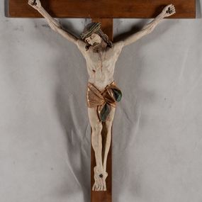 Zdjęcie nr 1: Rzeźba Chrystusa przybita do krzyża trzema gwoździami, pełna. Zbawiciel ukazany w typie Cristo morte, w lekkim zwisie, z głową pochyloną na prawą stronę. Jezus ma szczupłą sylwetkę ciała, duże stopy, delikatnie podkreśloną linię żeber. Jego twarz jest podłużna, ma długi nos, delikatnie otwarte usta i zamknięte oczy, krótką brodę, zwiniętą na końcu w dwa pukle. Ma długie, brązowe włosy spływające falami do przodu, a na głowie założoną koronę cierniową złożoną z prostych zielonych gałązek. Biodra oplata złocone perizonium z zieloną podszewką, zawiązane pośrodku. Z dłoni, stóp i boku Chrystusa spływają strużki krwi. Polichromia ciała naturalistyczna, perizonium złocone. Nad głową Jezusa titulus w formie banderoli z napisem „I. N. R. I.”. Krzyż prosty, gładki, malowany na brązowo.
