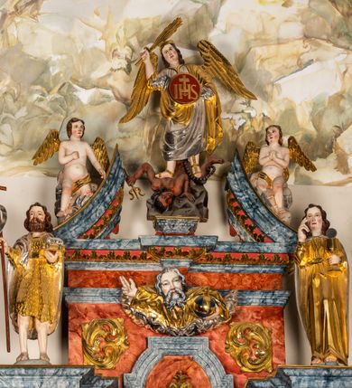 Zdjęcie nr 9: Ołtarz architektoniczny, jednondygnacyjny, jednoosiowy, ze zwieńczeniem. Ołtarz prostopadłościenny, z drewnianą mensą i kamiennym portatylem. Retabulum na niewysokim cokole o zryzalitowanych, uskokowych bokach. Retabulum ujęte parą zdwojonych filarów z przylegającymi do nich od wewnętrznej strony wąskimi pilastrami oraz parą kolumn wspierających przerwane, wyłamujące się po środku belkowanie. Zwieńczenie w formie przerwanego przyczółka w kształcie trójkąta o wklęsłych ramionach. 
Antependium,  pośrodku z motywem płaskorzeźbionego monogramu IHS i gorejącego Serca Jezusa ujętego wieńcem srebrzonych obłoków i promienistą glorią. Powierzchnia boków płyciny antependium pokryta wicią akantową. W polach cokołu dolnej kondygnacji retabulum i w dolnej partii części środkowej retabulum oraz w części belkowania ornamentyka akantowa. W górnej partii części środkowej, po środku niewielki cokolik zdobiony fragmentem wici akantowej zwieńczony półkulą z kwiatonem ujętym parą antytetycznych wolut. Dolna kondygnacja retabulum ujęta parą ażurowych, akantowych uszaków. Boki górnej kondygnacji zdobione motywem ornamentu akantowego. Partie gzymsu z ornamentyką roślinną. Pole części środkowej dolnej kondygnacji w kształcie stojącego prostokąta ujętego srebrzona i złoconą ramą w formie półwałka, zdobioną motywem liści laurowych. W środku obraz Serce Jezusa. W zwieńczeniu  rzeźbione popiersie Boga Ojca. Kondygnacja ta ujęta parą rzeźb św. Jana Chrzciciela po lewej stronie i św. Jana Ewangelisty po prawej. Po środku zwieńczenia figura Archanioła Michała. Na krawędziach przerwanego przyczółka para aniołków przyklękających na srebrzonych obłokach.
Struktura marmoryzowana w odcieniach brązów i szarości. Partie detalu architektonicznego i ornamentyka złocone i srebrzone.         
