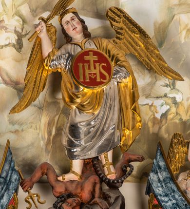 Zdjęcie nr 4: Ołtarz architektoniczny, jednondygnacyjny, jednoosiowy, ze zwieńczeniem. Ołtarz prostopadłościenny, z drewnianą mensą i kamiennym portatylem. Retabulum na niewysokim cokole o zryzalitowanych, uskokowych bokach. Retabulum ujęte parą zdwojonych filarów z przylegającymi do nich od wewnętrznej strony wąskimi pilastrami oraz parą kolumn wspierających przerwane, wyłamujące się po środku belkowanie. Zwieńczenie w formie przerwanego przyczółka w kształcie trójkąta o wklęsłych ramionach. 
Antependium,  pośrodku z motywem płaskorzeźbionego monogramu IHS i gorejącego Serca Jezusa ujętego wieńcem srebrzonych obłoków i promienistą glorią. Powierzchnia boków płyciny antependium pokryta wicią akantową. W polach cokołu dolnej kondygnacji retabulum i w dolnej partii części środkowej retabulum oraz w części belkowania ornamentyka akantowa. W górnej partii części środkowej, po środku niewielki cokolik zdobiony fragmentem wici akantowej zwieńczony półkulą z kwiatonem ujętym parą antytetycznych wolut. Dolna kondygnacja retabulum ujęta parą ażurowych, akantowych uszaków. Boki górnej kondygnacji zdobione motywem ornamentu akantowego. Partie gzymsu z ornamentyką roślinną. Pole części środkowej dolnej kondygnacji w kształcie stojącego prostokąta ujętego srebrzona i złoconą ramą w formie półwałka, zdobioną motywem liści laurowych. W środku obraz Serce Jezusa. W zwieńczeniu  rzeźbione popiersie Boga Ojca. Kondygnacja ta ujęta parą rzeźb św. Jana Chrzciciela po lewej stronie i św. Jana Ewangelisty po prawej. Po środku zwieńczenia figura Archanioła Michała. Na krawędziach przerwanego przyczółka para aniołków przyklękających na srebrzonych obłokach.
Struktura marmoryzowana w odcieniach brązów i szarości. Partie detalu architektonicznego i ornamentyka złocone i srebrzone.         
