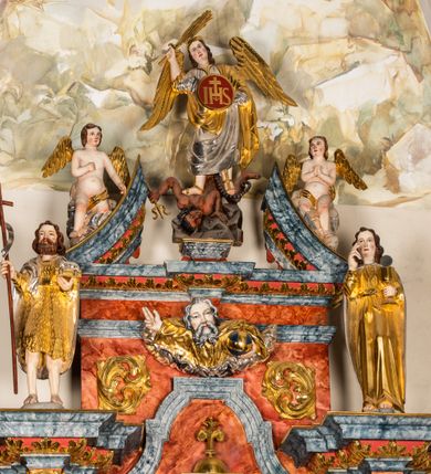 Zdjęcie nr 10: Ołtarz architektoniczny, jednondygnacyjny, jednoosiowy, ze zwieńczeniem. Ołtarz prostopadłościenny, z drewnianą mensą i kamiennym portatylem. Retabulum na niewysokim cokole o zryzalitowanych, uskokowych bokach. Retabulum ujęte parą zdwojonych filarów z przylegającymi do nich od wewnętrznej strony wąskimi pilastrami oraz parą kolumn wspierających przerwane, wyłamujące się po środku belkowanie. Zwieńczenie w formie przerwanego przyczółka w kształcie trójkąta o wklęsłych ramionach. 
Antependium,  pośrodku z motywem płaskorzeźbionego monogramu IHS i gorejącego Serca Jezusa ujętego wieńcem srebrzonych obłoków i promienistą glorią. Powierzchnia boków płyciny antependium pokryta wicią akantową. W polach cokołu dolnej kondygnacji retabulum i w dolnej partii części środkowej retabulum oraz w części belkowania ornamentyka akantowa. W górnej partii części środkowej, po środku niewielki cokolik zdobiony fragmentem wici akantowej zwieńczony półkulą z kwiatonem ujętym parą antytetycznych wolut. Dolna kondygnacja retabulum ujęta parą ażurowych, akantowych uszaków. Boki górnej kondygnacji zdobione motywem ornamentu akantowego. Partie gzymsu z ornamentyką roślinną. Pole części środkowej dolnej kondygnacji w kształcie stojącego prostokąta ujętego srebrzona i złoconą ramą w formie półwałka, zdobioną motywem liści laurowych. W środku obraz Serce Jezusa. W zwieńczeniu  rzeźbione popiersie Boga Ojca. Kondygnacja ta ujęta parą rzeźb św. Jana Chrzciciela po lewej stronie i św. Jana Ewangelisty po prawej. Po środku zwieńczenia figura Archanioła Michała. Na krawędziach przerwanego przyczółka para aniołków przyklękających na srebrzonych obłokach.
Struktura marmoryzowana w odcieniach brązów i szarości. Partie detalu architektonicznego i ornamentyka złocone i srebrzone.         
