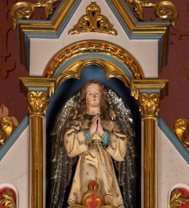 Zdjęcie nr 11: Ołtarz przyścienny, architektoniczny, jednokondygnacyjny, trójosiowy, ze zwieńczeniem. Ołtarz prostopadłościenny z antepedium artykułowanym trzema płycinami. Dwie skrajne, węższe zawierają dekorację złożoną z korony i nasadzonego na nią krzyża pomiędzy liśćmi wawrzynu ustawionymi w słup, środkowa, szersza z motywem krzyża równoramiennego o trójlistnych zakończeniach ramion, ujętego maswerkiem. Predella wklęśle zwężająca się, po bokach artykułowana pięcioma płycinami ze stylizowanymi wiciami roślinnymi. Tabernakulum w formie prostopadłościennej szafki, flankowane od frontu parą kolumienek wtopionych w naroża, zamknięte nadwieszonym łukiem półkolistym. Prostokątne, półkoliście zamknięte drzwiczki zdobione płaskorzeźbionym motywem kielicha eucharystycznego.  Część środkowa nastawy w formie trójprzelotowego łuku triumfalnego. Każda z ujmujących płytkie wnęki półkolistych arkad wsparta na parze kolumn. Podłucza ujęte dekoracyjnym ornamentem arkadkowym, który w części środkowej przybiera kształt trójliścia. Kolumny wspierają zamykające osie wimpergi. Zwieńczenie części środkowej retabulum osadzone na zdwojonym cokole, ma formę wspartej na parze kolumienek półkolistej arkady, której podłucze wypełnia motyw trójliścia, zamkniętej wimpergą. Całość ujmuje para przypór o zakończeniach ujętych kolumienkami wspierającymi sterczyny. Boczne osie zwieńczone motywem oktogonalnych latarni przekrytych kopułkami. Pola predelli zdobią motywy wici akantowych, boki ujmuje para ażurowych uszaków. W polach wimperg oraz w dolnej partii wnęki części środkowej stylizowana ornamentyka roślinna, w górnej części monogram maryjny. Krawędzie zwieńczenia zdobi motyw wici roślinnej, czołganki oraz sterczyny zwieńczone kwiatonami. We wnęce części środkowej ujęty rzeźbioną, złoconą ramą obraz Matki Boskiej z Dzieciątkiem. We wnęce po prawej stronie retabulum figura św. Stanisława Kostki, po lewej św. Alojzego Gonzagi. W zwieńczeniu figura anioła. Polichromia ołtarza utrzymana w kolorach beżu i różu, detale i ornamenty złocone. Kolumny środkowej osi zielone, marmoryzowane, gzymsy w przyczółkach w kolorach niebieskim i czerwonym.