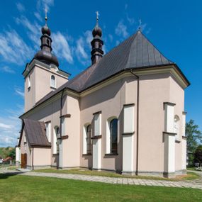 Zdjęcie nr 1: Kościół orientowany, jest budowlą murowaną z cegły i kamienia, na rzucie podłużnym. Korpus nawowy jest jednonawowy i czteroprzęsłowy. Do dwuprzęsłowego, zamkniętego trójbocznie prezbiterium od północy przylega zakrystia. Na osi kościoła, w przedłużeniu północnego przęsła jest czworoboczna, wysunięta przed lico fasady wieża. Od południa do drugiego przęsła korpusu przylega kruchta. Nawa przekryta jest sklepieniem kolebkowym z lunetami wspartymi na pilastrach, w prezbiterium sklepienie krzyżowo-żebrowe z gurtą wspartą na pilastrach. Przestrzeń prezbiterium od korpusu nawowego oddziela półkolista arkada łuku tęczowego i drewniana balustrada. Artykulację ścian na zewnątrz kościoła stanowi zespół dwuuskokowych przypór, w narożach wieży są czterouskokowe, osadzonych na niewysokim cokole. Do wnętrza prowadzą 3 otwory drzwiowe. Dwuskrzydłowe drzwi w fasadzie ujęte są kamiennym obramieniem zamkniętym łukiem koszowym z kluczem pośrodku, wspartym na gzymsie oraz 2 w północnej ścianie kaplicy bocznej. 2 prostokątne prowadzą przez kruchtę i zakrystię. Ściany korpusu nawowego i prezbiterium przeprute są prostokątnymi oknami zamkniętymi łukiem odcinkowym. Okno na zakończeniu prezbiterium jest formie półkoliście zamkniętej niszy z figurą Matki Boskiej. Kształt okien korpusu i prezbiterium został powtórzony w przyległości prezbiterium. Powyżej wejścia na osi wieży małe okienko zamknięte łukiem koszowym, wyżej nisza zamknięta ostrołukowo. W górnej partii wieży znajdują się cztery, duże, zamknięte półkoliście otwory okienne ujęte prostymi obramieniami. Szczyt wierzy obiega gzyms wieńczący z półkolistym łukiem na osi każdej ze ścian. Dach w formie hełmu z latarnią. Dach prezbiterium i korpusu dwuspadowy, kryty blachą, nad pierwszym przęsłem wieżyczka na sygnaturkę. Kruchta z dachem dwuspadowym, przyległość pulpitowym. Tynki w kolorze beżowym i białym. 