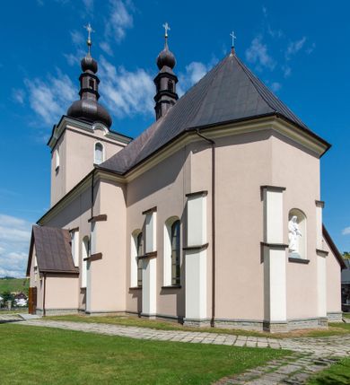 Zdjęcie nr 46: Kościół orientowany, jest budowlą murowaną z cegły i kamienia, na rzucie podłużnym. Korpus nawowy jest jednonawowy i czteroprzęsłowy. Do dwuprzęsłowego, zamkniętego trójbocznie prezbiterium od północy przylega zakrystia. Na osi kościoła, w przedłużeniu północnego przęsła jest czworoboczna, wysunięta przed lico fasady wieża. Od południa do drugiego przęsła korpusu przylega kruchta. Nawa przekryta jest sklepieniem kolebkowym z lunetami wspartymi na pilastrach, w prezbiterium sklepienie krzyżowo-żebrowe z gurtą wspartą na pilastrach. Przestrzeń prezbiterium od korpusu nawowego oddziela półkolista arkada łuku tęczowego i drewniana balustrada. Artykulację ścian na zewnątrz kościoła stanowi zespół dwuuskokowych przypór, w narożach wieży są czterouskokowe, osadzonych na niewysokim cokole. Do wnętrza prowadzą 3 otwory drzwiowe. Dwuskrzydłowe drzwi w fasadzie ujęte są kamiennym obramieniem zamkniętym łukiem koszowym z kluczem pośrodku, wspartym na gzymsie oraz 2 w północnej ścianie kaplicy bocznej. 2 prostokątne prowadzą przez kruchtę i zakrystię. Ściany korpusu nawowego i prezbiterium przeprute są prostokątnymi oknami zamkniętymi łukiem odcinkowym. Okno na zakończeniu prezbiterium jest formie półkoliście zamkniętej niszy z figurą Matki Boskiej. Kształt okien korpusu i prezbiterium został powtórzony w przyległości prezbiterium. Powyżej wejścia na osi wieży małe okienko zamknięte łukiem koszowym, wyżej nisza zamknięta ostrołukowo. W górnej partii wieży znajdują się cztery, duże, zamknięte półkoliście otwory okienne ujęte prostymi obramieniami. Szczyt wierzy obiega gzyms wieńczący z półkolistym łukiem na osi każdej ze ścian. Dach w formie hełmu z latarnią. Dach prezbiterium i korpusu dwuspadowy, kryty blachą, nad pierwszym przęsłem wieżyczka na sygnaturkę. Kruchta z dachem dwuspadowym, przyległość pulpitowym. Tynki w kolorze beżowym i białym. 