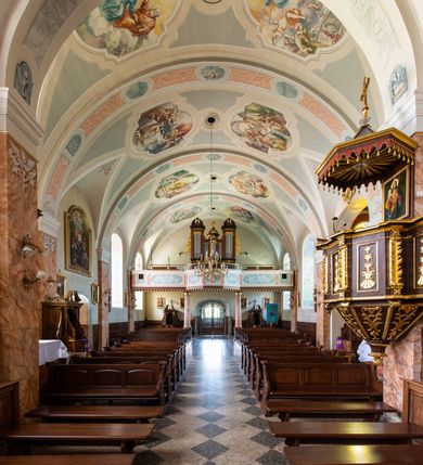 Zdjęcie nr 33: Kościół orientowany, jest budowlą murowaną z cegły i kamienia, na rzucie podłużnym. Korpus nawowy jest jednonawowy i czteroprzęsłowy. Do dwuprzęsłowego, zamkniętego trójbocznie prezbiterium od północy przylega zakrystia. Na osi kościoła, w przedłużeniu północnego przęsła jest czworoboczna, wysunięta przed lico fasady wieża. Od południa do drugiego przęsła korpusu przylega kruchta. Nawa przekryta jest sklepieniem kolebkowym z lunetami wspartymi na pilastrach, w prezbiterium sklepienie krzyżowo-żebrowe z gurtą wspartą na pilastrach. Przestrzeń prezbiterium od korpusu nawowego oddziela półkolista arkada łuku tęczowego i drewniana balustrada. Artykulację ścian na zewnątrz kościoła stanowi zespół dwuuskokowych przypór, w narożach wieży są czterouskokowe, osadzonych na niewysokim cokole. Do wnętrza prowadzą 3 otwory drzwiowe. Dwuskrzydłowe drzwi w fasadzie ujęte są kamiennym obramieniem zamkniętym łukiem koszowym z kluczem pośrodku, wspartym na gzymsie oraz 2 w północnej ścianie kaplicy bocznej. 2 prostokątne prowadzą przez kruchtę i zakrystię. Ściany korpusu nawowego i prezbiterium przeprute są prostokątnymi oknami zamkniętymi łukiem odcinkowym. Okno na zakończeniu prezbiterium jest formie półkoliście zamkniętej niszy z figurą Matki Boskiej. Kształt okien korpusu i prezbiterium został powtórzony w przyległości prezbiterium. Powyżej wejścia na osi wieży małe okienko zamknięte łukiem koszowym, wyżej nisza zamknięta ostrołukowo. W górnej partii wieży znajdują się cztery, duże, zamknięte półkoliście otwory okienne ujęte prostymi obramieniami. Szczyt wierzy obiega gzyms wieńczący z półkolistym łukiem na osi każdej ze ścian. Dach w formie hełmu z latarnią. Dach prezbiterium i korpusu dwuspadowy, kryty blachą, nad pierwszym przęsłem wieżyczka na sygnaturkę. Kruchta z dachem dwuspadowym, przyległość pulpitowym. Tynki w kolorze beżowym i białym. 