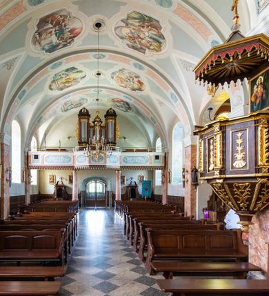 Zdjęcie nr 39: Kościół orientowany, jest budowlą murowaną z cegły i kamienia, na rzucie podłużnym. Korpus nawowy jest jednonawowy i czteroprzęsłowy. Do dwuprzęsłowego, zamkniętego trójbocznie prezbiterium od północy przylega zakrystia. Na osi kościoła, w przedłużeniu północnego przęsła jest czworoboczna, wysunięta przed lico fasady wieża. Od południa do drugiego przęsła korpusu przylega kruchta. Nawa przekryta jest sklepieniem kolebkowym z lunetami wspartymi na pilastrach, w prezbiterium sklepienie krzyżowo-żebrowe z gurtą wspartą na pilastrach. Przestrzeń prezbiterium od korpusu nawowego oddziela półkolista arkada łuku tęczowego i drewniana balustrada. Artykulację ścian na zewnątrz kościoła stanowi zespół dwuuskokowych przypór, w narożach wieży są czterouskokowe, osadzonych na niewysokim cokole. Do wnętrza prowadzą 3 otwory drzwiowe. Dwuskrzydłowe drzwi w fasadzie ujęte są kamiennym obramieniem zamkniętym łukiem koszowym z kluczem pośrodku, wspartym na gzymsie oraz 2 w północnej ścianie kaplicy bocznej. 2 prostokątne prowadzą przez kruchtę i zakrystię. Ściany korpusu nawowego i prezbiterium przeprute są prostokątnymi oknami zamkniętymi łukiem odcinkowym. Okno na zakończeniu prezbiterium jest formie półkoliście zamkniętej niszy z figurą Matki Boskiej. Kształt okien korpusu i prezbiterium został powtórzony w przyległości prezbiterium. Powyżej wejścia na osi wieży małe okienko zamknięte łukiem koszowym, wyżej nisza zamknięta ostrołukowo. W górnej partii wieży znajdują się cztery, duże, zamknięte półkoliście otwory okienne ujęte prostymi obramieniami. Szczyt wierzy obiega gzyms wieńczący z półkolistym łukiem na osi każdej ze ścian. Dach w formie hełmu z latarnią. Dach prezbiterium i korpusu dwuspadowy, kryty blachą, nad pierwszym przęsłem wieżyczka na sygnaturkę. Kruchta z dachem dwuspadowym, przyległość pulpitowym. Tynki w kolorze beżowym i białym. 