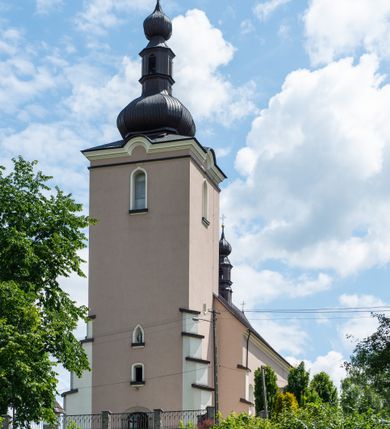 Zdjęcie nr 10: Kościół orientowany, jest budowlą murowaną z cegły i kamienia, na rzucie podłużnym. Korpus nawowy jest jednonawowy i czteroprzęsłowy. Do dwuprzęsłowego, zamkniętego trójbocznie prezbiterium od północy przylega zakrystia. Na osi kościoła, w przedłużeniu północnego przęsła jest czworoboczna, wysunięta przed lico fasady wieża. Od południa do drugiego przęsła korpusu przylega kruchta. Nawa przekryta jest sklepieniem kolebkowym z lunetami wspartymi na pilastrach, w prezbiterium sklepienie krzyżowo-żebrowe z gurtą wspartą na pilastrach. Przestrzeń prezbiterium od korpusu nawowego oddziela półkolista arkada łuku tęczowego i drewniana balustrada. Artykulację ścian na zewnątrz kościoła stanowi zespół dwuuskokowych przypór, w narożach wieży są czterouskokowe, osadzonych na niewysokim cokole. Do wnętrza prowadzą 3 otwory drzwiowe. Dwuskrzydłowe drzwi w fasadzie ujęte są kamiennym obramieniem zamkniętym łukiem koszowym z kluczem pośrodku, wspartym na gzymsie oraz 2 w północnej ścianie kaplicy bocznej. 2 prostokątne prowadzą przez kruchtę i zakrystię. Ściany korpusu nawowego i prezbiterium przeprute są prostokątnymi oknami zamkniętymi łukiem odcinkowym. Okno na zakończeniu prezbiterium jest formie półkoliście zamkniętej niszy z figurą Matki Boskiej. Kształt okien korpusu i prezbiterium został powtórzony w przyległości prezbiterium. Powyżej wejścia na osi wieży małe okienko zamknięte łukiem koszowym, wyżej nisza zamknięta ostrołukowo. W górnej partii wieży znajdują się cztery, duże, zamknięte półkoliście otwory okienne ujęte prostymi obramieniami. Szczyt wierzy obiega gzyms wieńczący z półkolistym łukiem na osi każdej ze ścian. Dach w formie hełmu z latarnią. Dach prezbiterium i korpusu dwuspadowy, kryty blachą, nad pierwszym przęsłem wieżyczka na sygnaturkę. Kruchta z dachem dwuspadowym, przyległość pulpitowym. Tynki w kolorze beżowym i białym. 