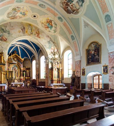 Zdjęcie nr 28: Kościół orientowany, jest budowlą murowaną z cegły i kamienia, na rzucie podłużnym. Korpus nawowy jest jednonawowy i czteroprzęsłowy. Do dwuprzęsłowego, zamkniętego trójbocznie prezbiterium od północy przylega zakrystia. Na osi kościoła, w przedłużeniu północnego przęsła jest czworoboczna, wysunięta przed lico fasady wieża. Od południa do drugiego przęsła korpusu przylega kruchta. Nawa przekryta jest sklepieniem kolebkowym z lunetami wspartymi na pilastrach, w prezbiterium sklepienie krzyżowo-żebrowe z gurtą wspartą na pilastrach. Przestrzeń prezbiterium od korpusu nawowego oddziela półkolista arkada łuku tęczowego i drewniana balustrada. Artykulację ścian na zewnątrz kościoła stanowi zespół dwuuskokowych przypór, w narożach wieży są czterouskokowe, osadzonych na niewysokim cokole. Do wnętrza prowadzą 3 otwory drzwiowe. Dwuskrzydłowe drzwi w fasadzie ujęte są kamiennym obramieniem zamkniętym łukiem koszowym z kluczem pośrodku, wspartym na gzymsie oraz 2 w północnej ścianie kaplicy bocznej. 2 prostokątne prowadzą przez kruchtę i zakrystię. Ściany korpusu nawowego i prezbiterium przeprute są prostokątnymi oknami zamkniętymi łukiem odcinkowym. Okno na zakończeniu prezbiterium jest formie półkoliście zamkniętej niszy z figurą Matki Boskiej. Kształt okien korpusu i prezbiterium został powtórzony w przyległości prezbiterium. Powyżej wejścia na osi wieży małe okienko zamknięte łukiem koszowym, wyżej nisza zamknięta ostrołukowo. W górnej partii wieży znajdują się cztery, duże, zamknięte półkoliście otwory okienne ujęte prostymi obramieniami. Szczyt wierzy obiega gzyms wieńczący z półkolistym łukiem na osi każdej ze ścian. Dach w formie hełmu z latarnią. Dach prezbiterium i korpusu dwuspadowy, kryty blachą, nad pierwszym przęsłem wieżyczka na sygnaturkę. Kruchta z dachem dwuspadowym, przyległość pulpitowym. Tynki w kolorze beżowym i białym. 