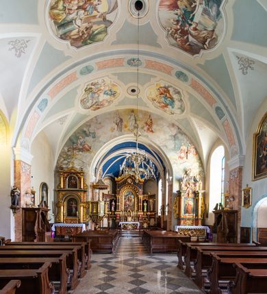 Zdjęcie nr 21: Kościół orientowany, jest budowlą murowaną z cegły i kamienia, na rzucie podłużnym. Korpus nawowy jest jednonawowy i czteroprzęsłowy. Do dwuprzęsłowego, zamkniętego trójbocznie prezbiterium od północy przylega zakrystia. Na osi kościoła, w przedłużeniu północnego przęsła jest czworoboczna, wysunięta przed lico fasady wieża. Od południa do drugiego przęsła korpusu przylega kruchta. Nawa przekryta jest sklepieniem kolebkowym z lunetami wspartymi na pilastrach, w prezbiterium sklepienie krzyżowo-żebrowe z gurtą wspartą na pilastrach. Przestrzeń prezbiterium od korpusu nawowego oddziela półkolista arkada łuku tęczowego i drewniana balustrada. Artykulację ścian na zewnątrz kościoła stanowi zespół dwuuskokowych przypór, w narożach wieży są czterouskokowe, osadzonych na niewysokim cokole. Do wnętrza prowadzą 3 otwory drzwiowe. Dwuskrzydłowe drzwi w fasadzie ujęte są kamiennym obramieniem zamkniętym łukiem koszowym z kluczem pośrodku, wspartym na gzymsie oraz 2 w północnej ścianie kaplicy bocznej. 2 prostokątne prowadzą przez kruchtę i zakrystię. Ściany korpusu nawowego i prezbiterium przeprute są prostokątnymi oknami zamkniętymi łukiem odcinkowym. Okno na zakończeniu prezbiterium jest formie półkoliście zamkniętej niszy z figurą Matki Boskiej. Kształt okien korpusu i prezbiterium został powtórzony w przyległości prezbiterium. Powyżej wejścia na osi wieży małe okienko zamknięte łukiem koszowym, wyżej nisza zamknięta ostrołukowo. W górnej partii wieży znajdują się cztery, duże, zamknięte półkoliście otwory okienne ujęte prostymi obramieniami. Szczyt wierzy obiega gzyms wieńczący z półkolistym łukiem na osi każdej ze ścian. Dach w formie hełmu z latarnią. Dach prezbiterium i korpusu dwuspadowy, kryty blachą, nad pierwszym przęsłem wieżyczka na sygnaturkę. Kruchta z dachem dwuspadowym, przyległość pulpitowym. Tynki w kolorze beżowym i białym. 