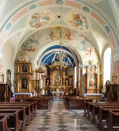 Zdjęcie nr 22: Kościół orientowany, jest budowlą murowaną z cegły i kamienia, na rzucie podłużnym. Korpus nawowy jest jednonawowy i czteroprzęsłowy. Do dwuprzęsłowego, zamkniętego trójbocznie prezbiterium od północy przylega zakrystia. Na osi kościoła, w przedłużeniu północnego przęsła jest czworoboczna, wysunięta przed lico fasady wieża. Od południa do drugiego przęsła korpusu przylega kruchta. Nawa przekryta jest sklepieniem kolebkowym z lunetami wspartymi na pilastrach, w prezbiterium sklepienie krzyżowo-żebrowe z gurtą wspartą na pilastrach. Przestrzeń prezbiterium od korpusu nawowego oddziela półkolista arkada łuku tęczowego i drewniana balustrada. Artykulację ścian na zewnątrz kościoła stanowi zespół dwuuskokowych przypór, w narożach wieży są czterouskokowe, osadzonych na niewysokim cokole. Do wnętrza prowadzą 3 otwory drzwiowe. Dwuskrzydłowe drzwi w fasadzie ujęte są kamiennym obramieniem zamkniętym łukiem koszowym z kluczem pośrodku, wspartym na gzymsie oraz 2 w północnej ścianie kaplicy bocznej. 2 prostokątne prowadzą przez kruchtę i zakrystię. Ściany korpusu nawowego i prezbiterium przeprute są prostokątnymi oknami zamkniętymi łukiem odcinkowym. Okno na zakończeniu prezbiterium jest formie półkoliście zamkniętej niszy z figurą Matki Boskiej. Kształt okien korpusu i prezbiterium został powtórzony w przyległości prezbiterium. Powyżej wejścia na osi wieży małe okienko zamknięte łukiem koszowym, wyżej nisza zamknięta ostrołukowo. W górnej partii wieży znajdują się cztery, duże, zamknięte półkoliście otwory okienne ujęte prostymi obramieniami. Szczyt wierzy obiega gzyms wieńczący z półkolistym łukiem na osi każdej ze ścian. Dach w formie hełmu z latarnią. Dach prezbiterium i korpusu dwuspadowy, kryty blachą, nad pierwszym przęsłem wieżyczka na sygnaturkę. Kruchta z dachem dwuspadowym, przyległość pulpitowym. Tynki w kolorze beżowym i białym. 