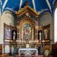 Zdjęcie nr 1: Ołtarz architektoniczny, jednokondygnacyjny, pięcioosiowy, na dwustrefowym cokole z bramkami w jego partii. Ołtarz prostopadłościenny, murowany, w drewnianej obudowie. Antepedium podzielone na trzy pola czterema pilastrami; w środkowym płaskorzeźbione serce ujęte krzyżem i kotwicą oraz kwiatami, w bocznych dekoracja roślinna. 
Tabernakulum w formie drewnianej skrzynki na planie prostokąta o ściętych przednich narożach, na profilowanym cokole, zamknięte gzymsem. Ścianka frontowa metalowa z drzwiczkami w formie stojącego prostokąta zamkniętego łukiem półkolistym z aplikowanym krzyżem z gorejącym sercem w glorii oraz winnym gronem i kłosami zbóż u spodu. Powyżej w przyłuczach aplikowana dekoracja w postaci winnego grona i kłosów zboża. Naroża i ścianki boczne dekorowane płycinami z płaskorzeźbionymi kwiatami i aplikowanymi metalowymi płytkami z kłosami zbóż. Na tabernakulum tron wystawienia w postaci baldachimu na czterech kolumienkach ze ścianką tylną z płaskorzeźbioną glorią promienistą. Baldachim o łukach ostrych, na froncie trójlistnym, z podwieszonymi wspornikami; całość zakończona krzyżem. 
Oś środkowa retabulum wyższa i szersza od pozostałych, ujęta dwiema parami stylizowanych kolumn dźwigającym archiwoltę oraz stylizowaną wimpergę, w której polu znajduje się fryz arkadkowy i medalion z płaskorzeźbioną Madonną z Dzieciątkiem (według Rafaela Santi), całość zamknięta trójkątnym gzymsem nadwieszonym, dekorowanym stylizowanym akantem, z krzyżem wieńczącym. W polu centralnym nisza w formie stojącego prostokąta zamkniętego łukiem półkolistym z wymiennymi figurami Matki Boskiej i Najświętszego Serca Jezusa, ujęta profilowaną ramą oraz pasem ornamentu roślinnego, na zasuwie wizerunek św. Marcina z Tours dzielącego się płaszczem z żebrakiem. Nisze boczne wydzielone wąskimi kolumienkami dźwigającymi niepełne belkowanie z dekoracją geometryczną i roślinną. W niszach środkowych na cokołach figury św. Piotra i św. Pawła; na osiach skrajnych malowane na desce przedstawienia św. Marcina jako mnicha po lewej stronie i św. Marcina jako biskupa po prawej. W dolnej partii strefy cokołu, na osiach wewnętrznych bramki w formie przejść; na skrajnych osiach siedziska. W partii drugiej strefy cokołu krenelaż, ornament ze stylizowanych lilii heraldycznych i płaskorzeźbiona dekoracja roślinna. Struktura w kolorze naturalnego drewna, z polichromowanymi na niebiesko i czerwono akcentami; ornamentyka i detale architektoniczne złocone.
